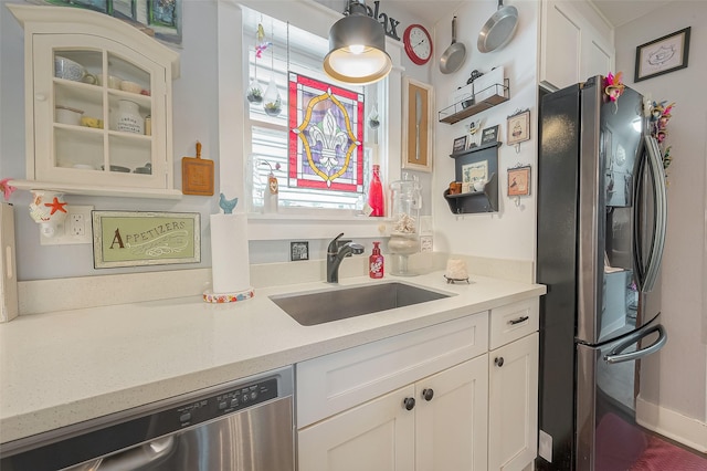 kitchen with hanging light fixtures, sink, white cabinets, and stainless steel appliances