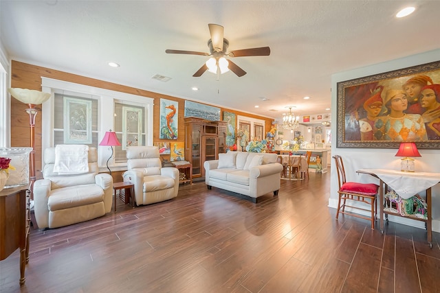 living room with ceiling fan with notable chandelier and dark hardwood / wood-style flooring