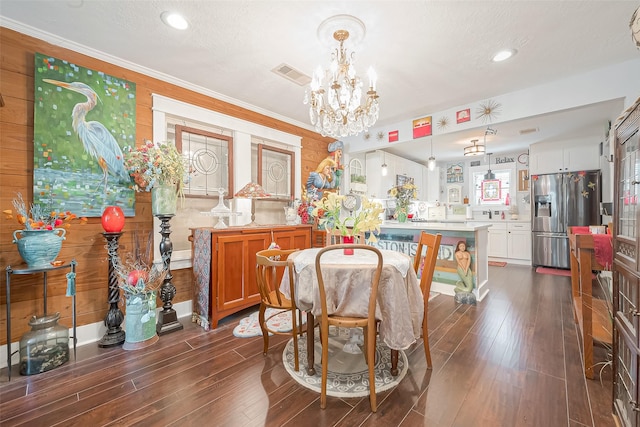 dining space with a notable chandelier, dark hardwood / wood-style flooring, ornamental molding, and wooden walls