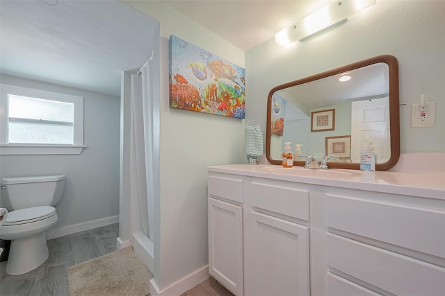 bathroom with hardwood / wood-style flooring, vanity, toilet, and walk in shower