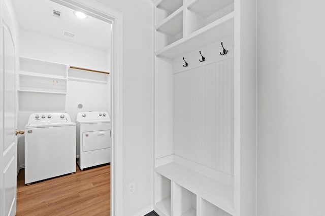 mudroom with light hardwood / wood-style floors and separate washer and dryer