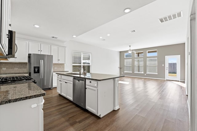 kitchen with a center island with sink, dark stone countertops, white cabinets, and stainless steel appliances