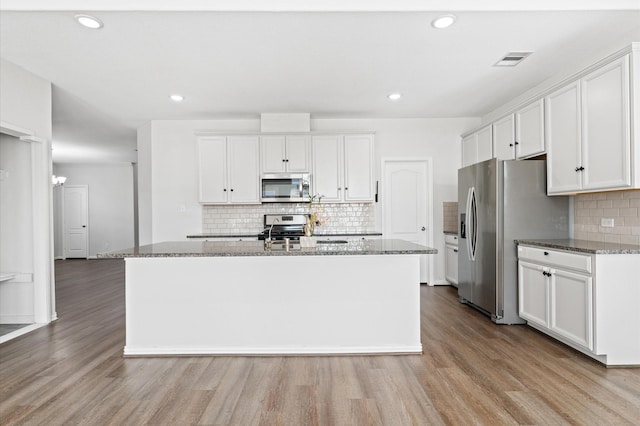 kitchen featuring white cabinetry, a center island with sink, light wood-type flooring, and appliances with stainless steel finishes