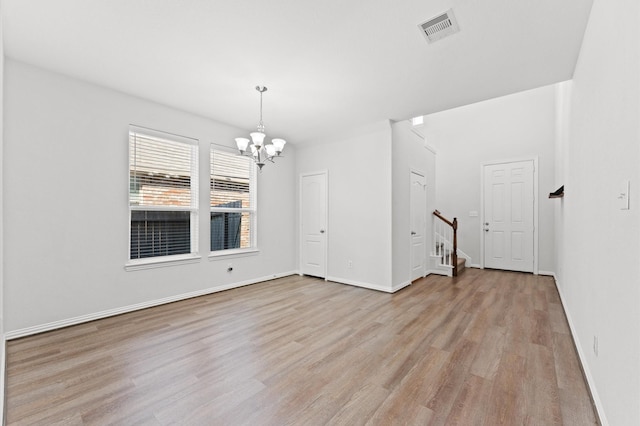 unfurnished room with a chandelier and light hardwood / wood-style flooring