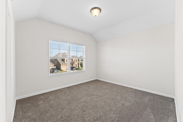 spare room featuring dark colored carpet and vaulted ceiling