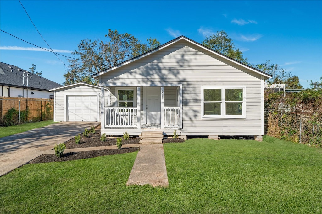 bungalow-style house with a porch, a garage, a front lawn, and an outdoor structure