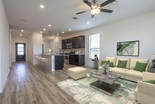 living room featuring ceiling fan and light hardwood / wood-style floors