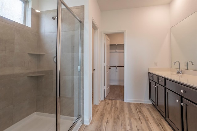 bathroom with hardwood / wood-style flooring, vanity, and a shower with door