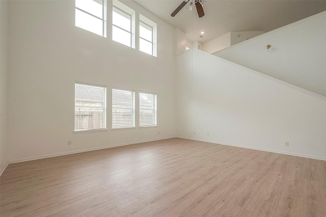 unfurnished living room featuring plenty of natural light, a high ceiling, and light wood-type flooring