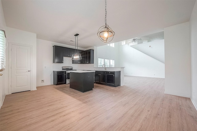 kitchen featuring gas range, ceiling fan, a center island, light hardwood / wood-style floors, and hanging light fixtures