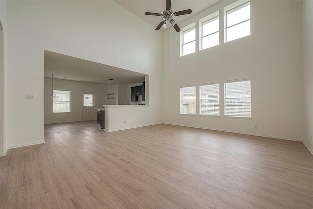 unfurnished living room with a high ceiling, light hardwood / wood-style flooring, and a healthy amount of sunlight