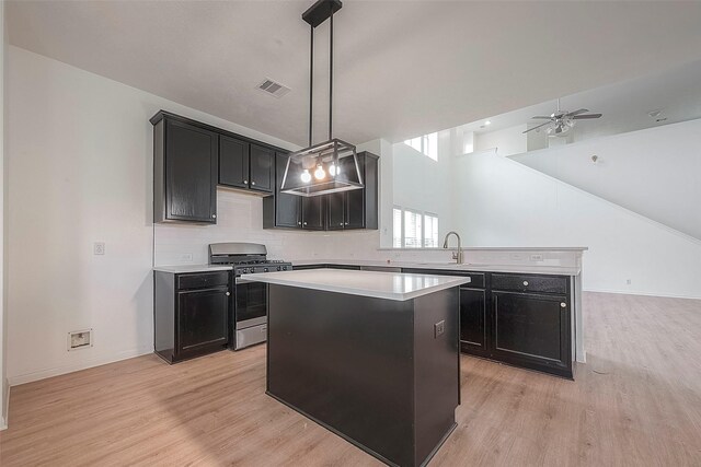 kitchen featuring sink, a center island, hanging light fixtures, stainless steel range with gas cooktop, and light wood-type flooring