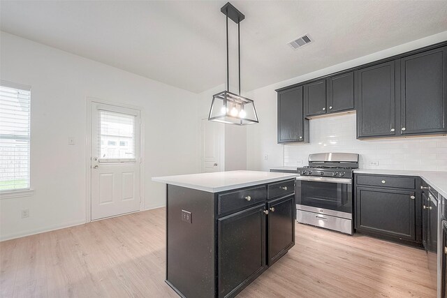 kitchen with pendant lighting, gas stove, a kitchen island, and a wealth of natural light