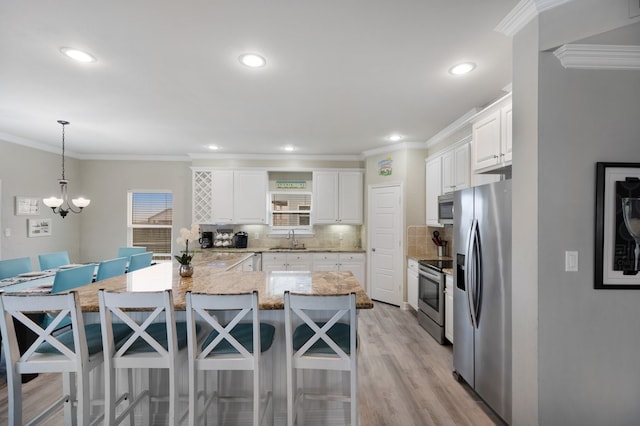 kitchen with pendant lighting, white cabinets, sink, tasteful backsplash, and stainless steel appliances