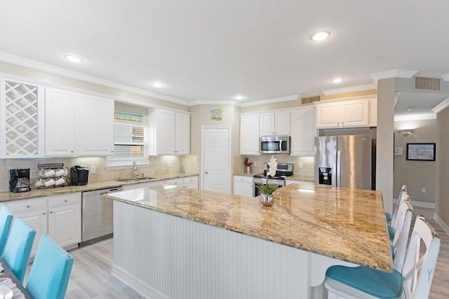 kitchen featuring appliances with stainless steel finishes, light stone counters, white cabinetry, and sink