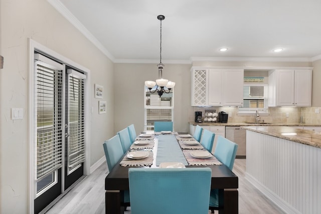 dining area with a chandelier, ornamental molding, sink, and light hardwood / wood-style flooring