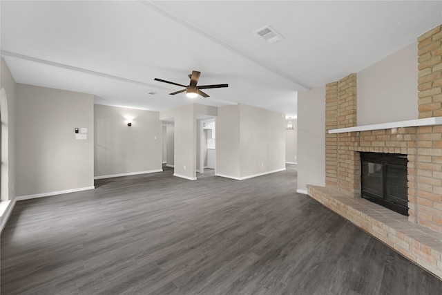 unfurnished living room with a brick fireplace, ceiling fan, and dark wood-type flooring