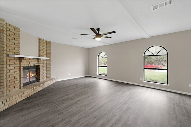 unfurnished living room featuring ceiling fan, beam ceiling, dark hardwood / wood-style flooring, and a fireplace