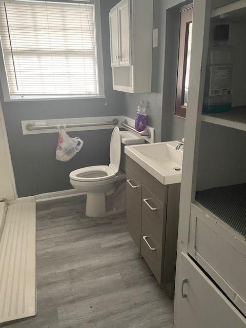 bathroom featuring hardwood / wood-style floors, vanity, a healthy amount of sunlight, and toilet