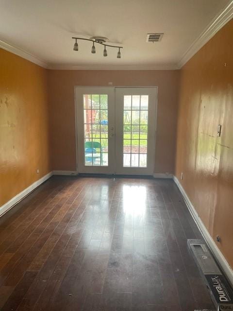 empty room featuring french doors, dark hardwood / wood-style floors, track lighting, and ornamental molding