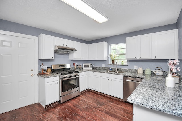 kitchen with light stone counters, stainless steel appliances, sink, white cabinets, and dark hardwood / wood-style floors