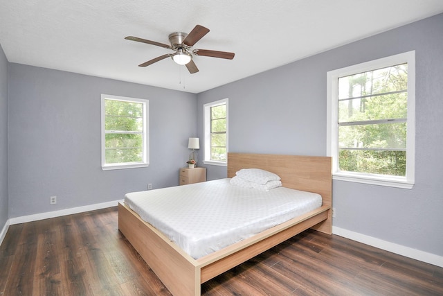 bedroom featuring dark hardwood / wood-style floors, ceiling fan, and multiple windows