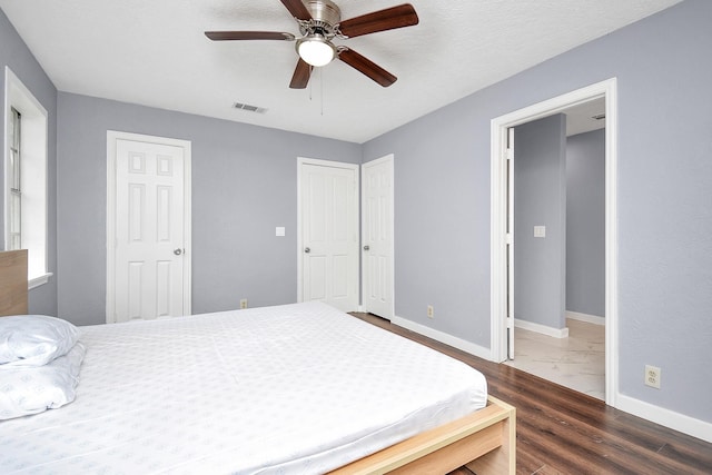 bedroom featuring ceiling fan, dark hardwood / wood-style floors, and a textured ceiling