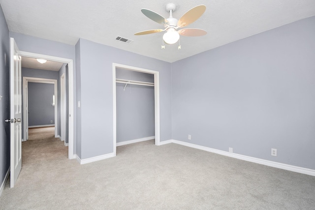 unfurnished bedroom with a textured ceiling, ceiling fan, light carpet, and a closet