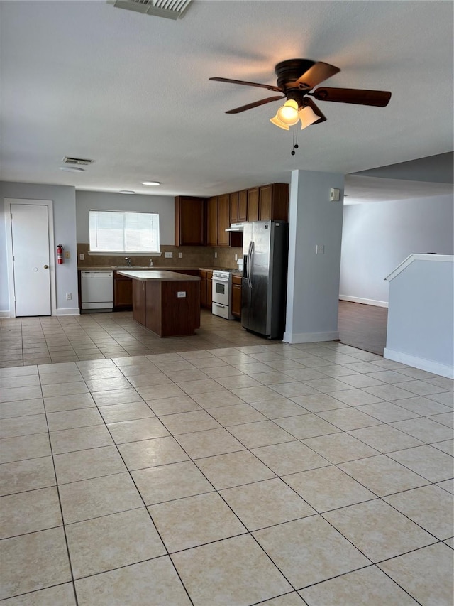 kitchen featuring a center island, white appliances, ceiling fan, decorative backsplash, and light tile patterned floors