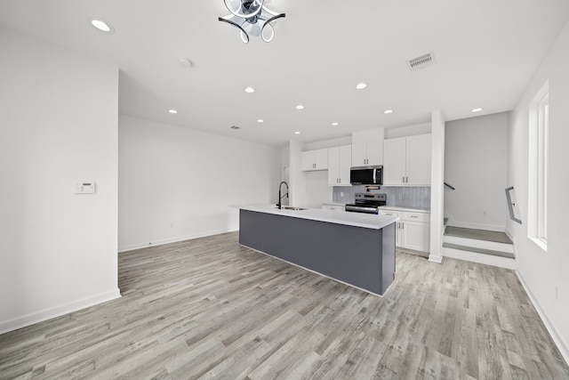 kitchen featuring white cabinetry, sink, light hardwood / wood-style floors, a kitchen island with sink, and appliances with stainless steel finishes