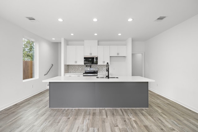 kitchen featuring appliances with stainless steel finishes, an island with sink, white cabinetry, and sink