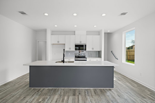 kitchen with a kitchen island with sink, sink, white cabinets, and appliances with stainless steel finishes