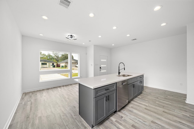 kitchen featuring a center island with sink, sink, stainless steel dishwasher, gray cabinets, and light hardwood / wood-style floors