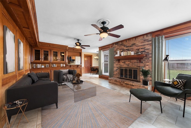 living room featuring wooden walls, ceiling fan, and a brick fireplace