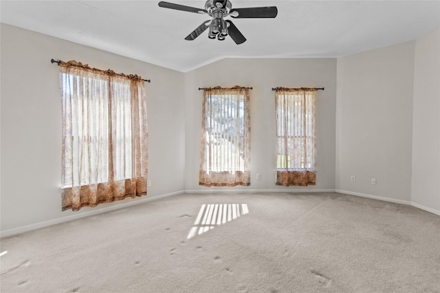 carpeted empty room featuring ceiling fan, a wealth of natural light, and vaulted ceiling