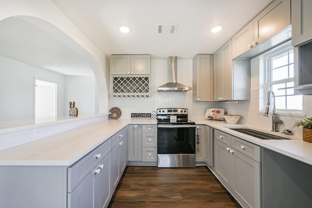 kitchen with gray cabinetry, stainless steel electric range, sink, and wall chimney range hood