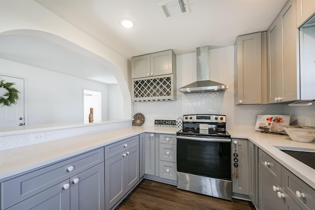 kitchen with wall chimney exhaust hood, dark hardwood / wood-style flooring, stainless steel electric range, gray cabinets, and decorative backsplash