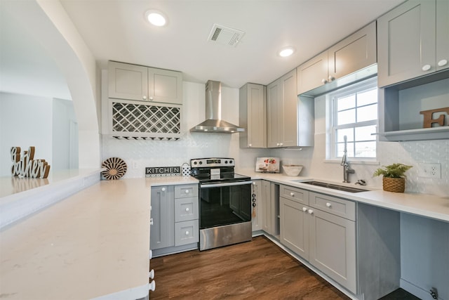 kitchen with gray cabinetry, dark wood-type flooring, sink, wall chimney range hood, and stainless steel electric range