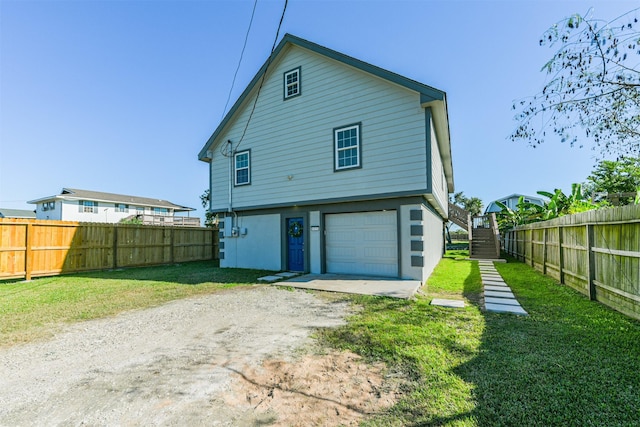 back of house featuring a yard and a garage