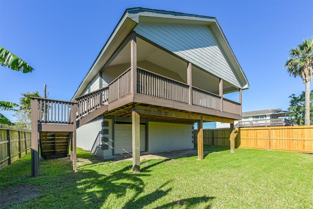 rear view of house featuring a garage, a yard, and a wooden deck