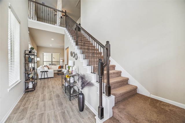 stairway featuring a towering ceiling and hardwood / wood-style flooring