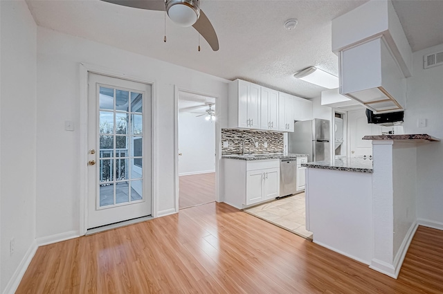 kitchen with white cabinetry, stainless steel appliances, light hardwood / wood-style flooring, kitchen peninsula, and decorative backsplash