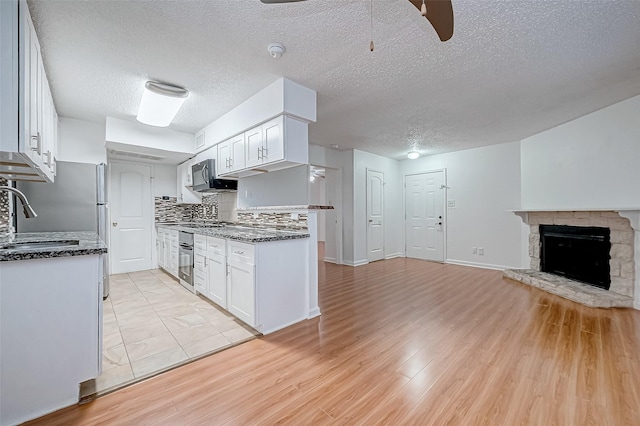 kitchen featuring dark stone countertops, white cabinetry, light hardwood / wood-style floors, and a textured ceiling