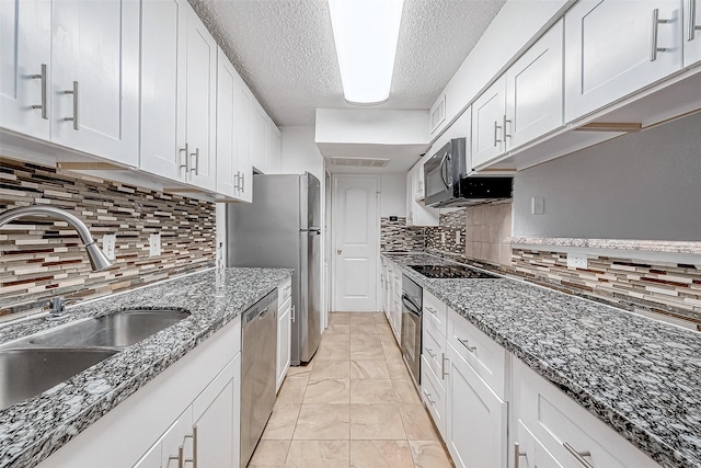 kitchen featuring backsplash, dark stone counters, white cabinets, black appliances, and sink