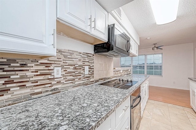 kitchen with backsplash, white cabinetry, black appliances, and a textured ceiling