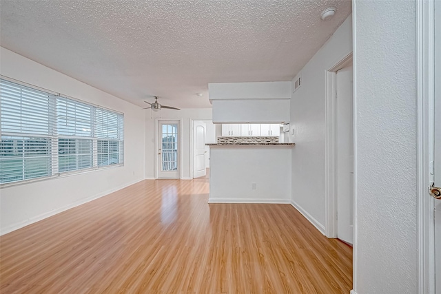 unfurnished living room with a textured ceiling, light hardwood / wood-style flooring, and ceiling fan