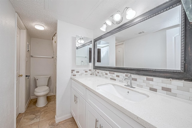 bathroom featuring backsplash, a textured ceiling, vanity, tile patterned flooring, and toilet