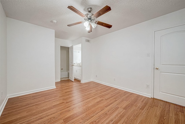 unfurnished bedroom featuring ceiling fan, a textured ceiling, connected bathroom, and light hardwood / wood-style flooring