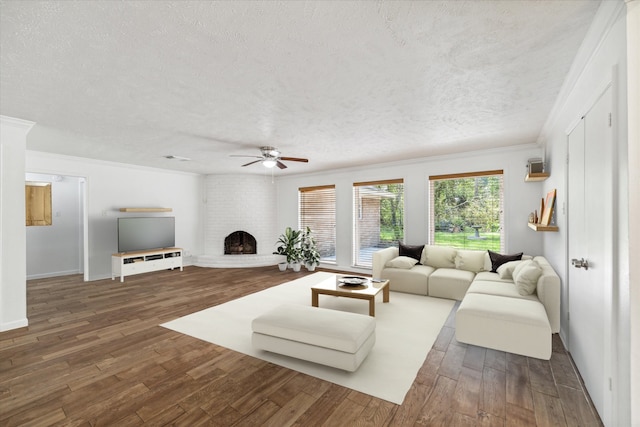 living room with ornamental molding, a textured ceiling, ceiling fan, a fireplace, and dark hardwood / wood-style floors