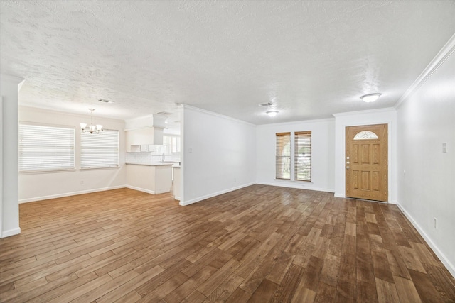 unfurnished living room featuring hardwood / wood-style flooring, ornamental molding, and a chandelier